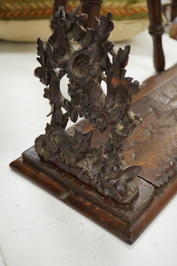 A Black Forest carved book-rack and a commemorative carved oak stool, for the Winchester college emblem, stool 39cm high